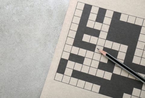 Blank crossword and pencil on old white table, top view. Space f