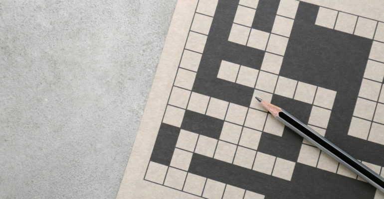 Blank crossword and pencil on old white table, top view. Space f